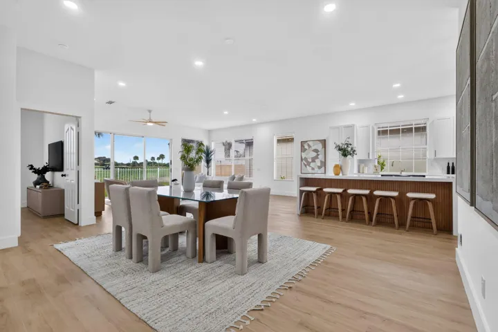 Open-concept living area featuring wood-finish flooring, recessed lighting, and a white kitchen with a peninsula island
