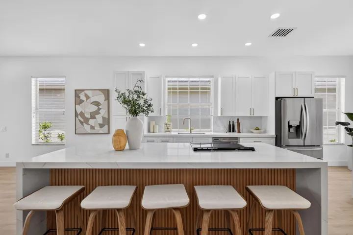 Quartz island countertop with wood-finish fluted paneling, integrated cooktop, and undermount sink