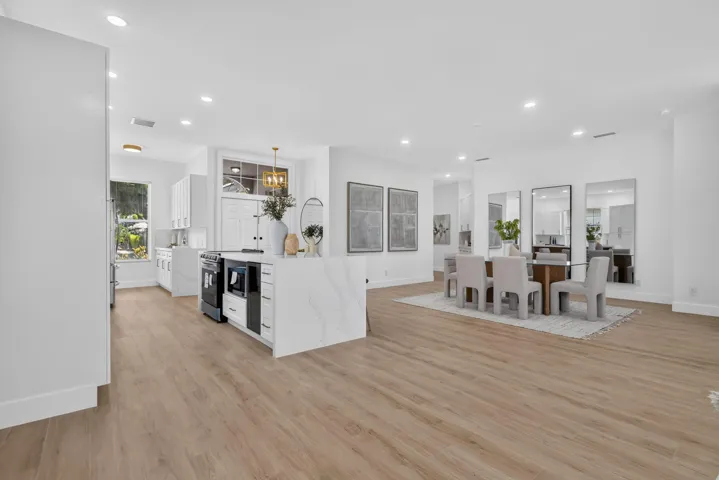 Open-concept living area featuring light wood-finish flooring, recessed lighting, and white walls