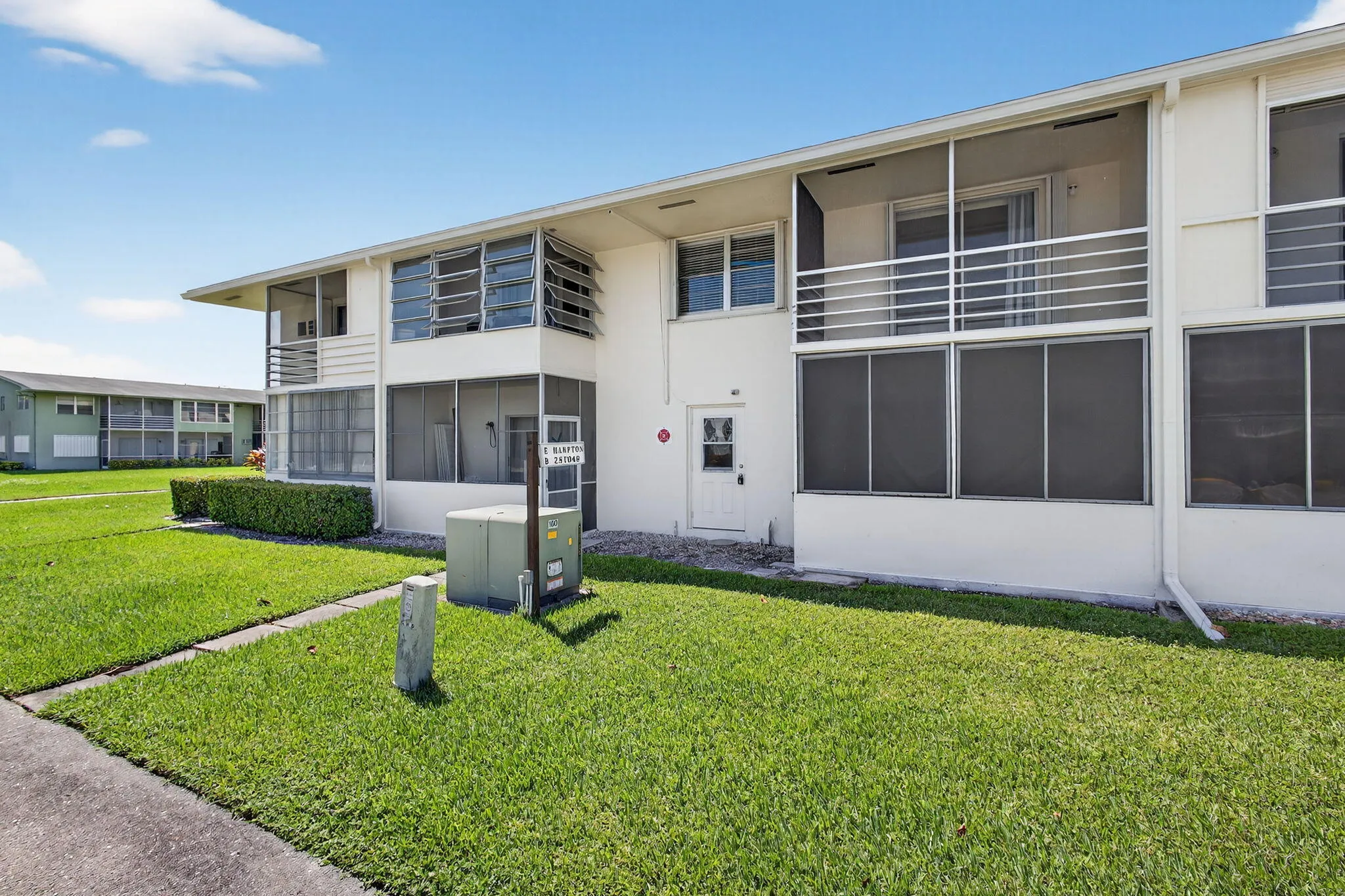 Two-story structure with white exterior finish, screened-in patios, and a second-level balcony with white railings