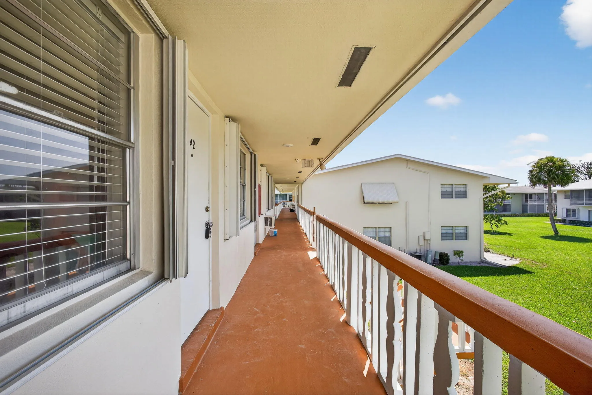 Covered exterior walkway with a painted surface and a wooden railing