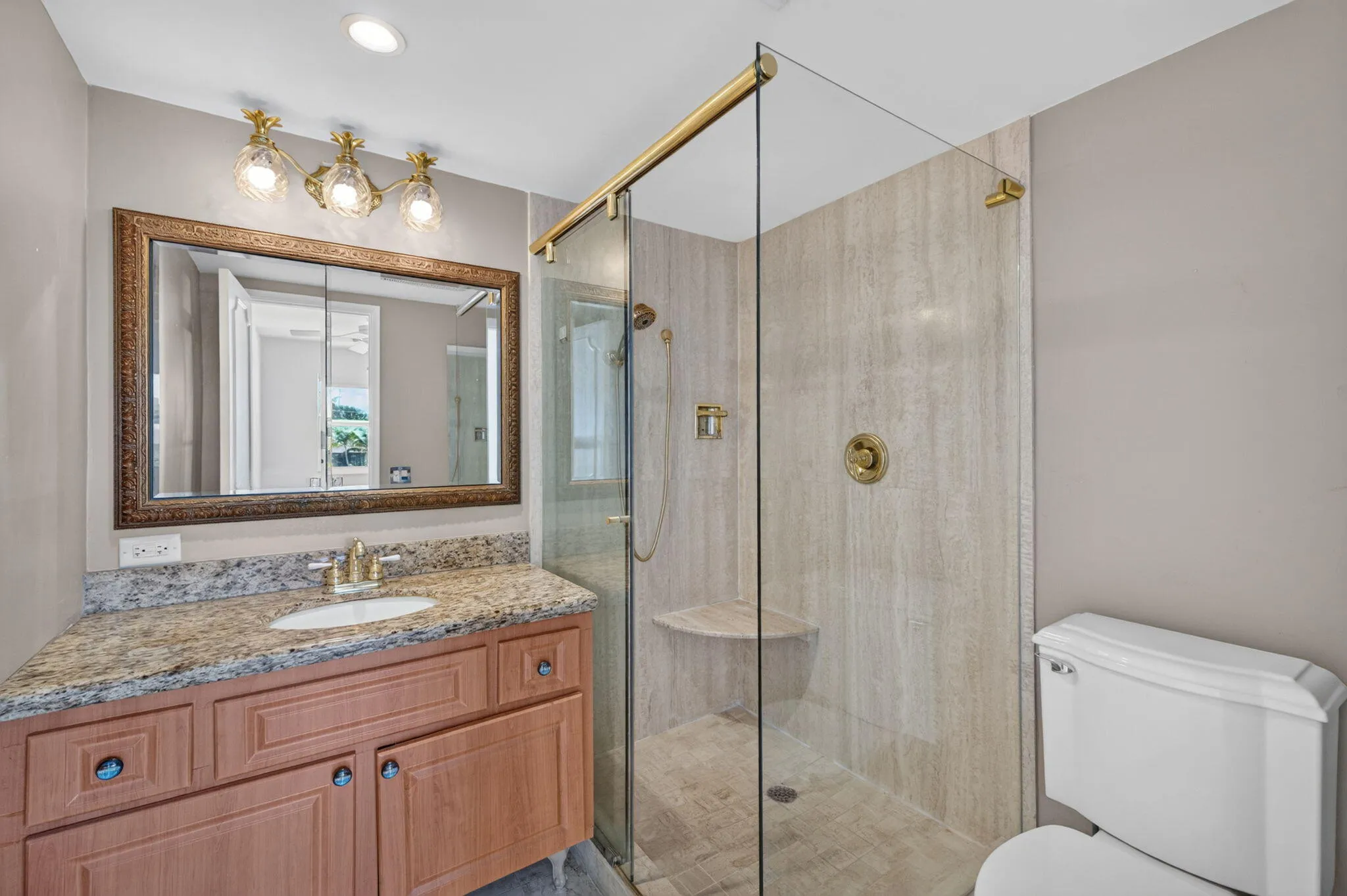 Vanity with a light-toned stone countertop, integrated sink, and an ornate framed mirror