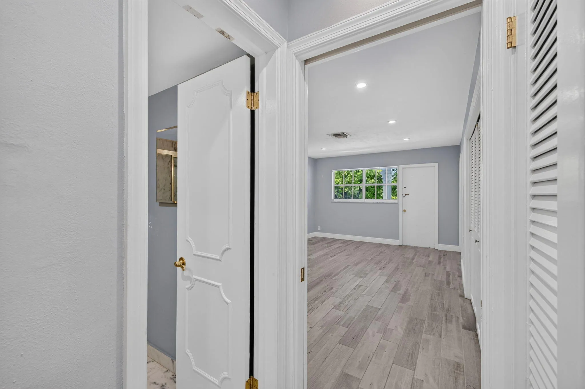 Recessed lighting, wood-finish flooring, and white trim