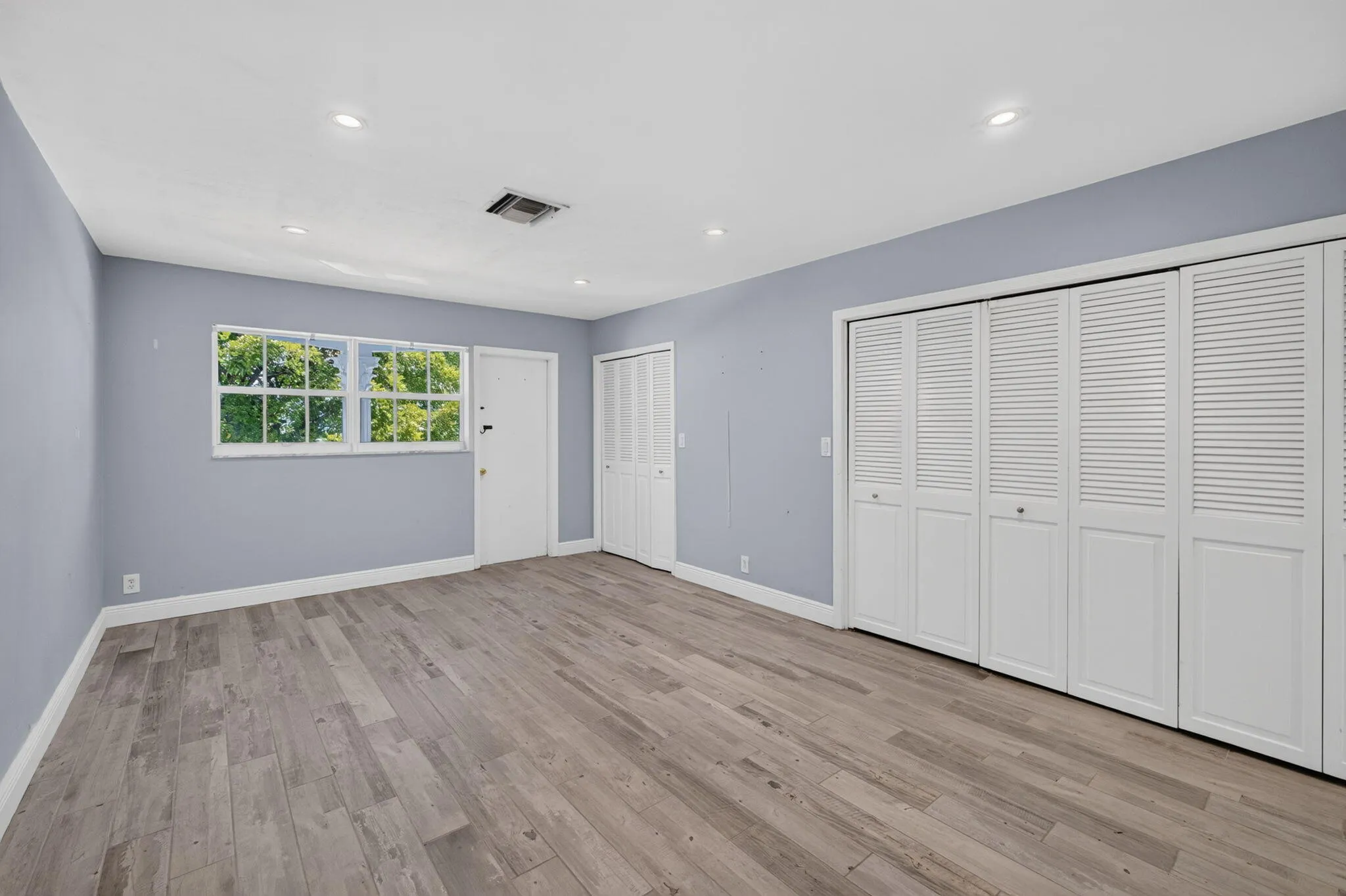 Recessed lighting, wood-finish flooring, white louvered bi-fold closet doors, and multiple windows