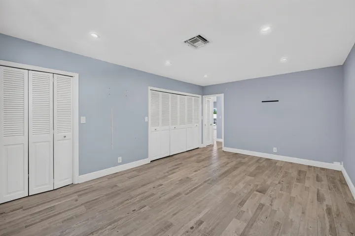 Recessed lighting, wood-finish flooring, two sets of louvered bi-fold closet doors, and light blue wall tones