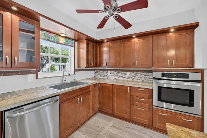Wood-finish cabinetry with recessed lighting, stainless steel appliances, and a mosaic tile backsplash