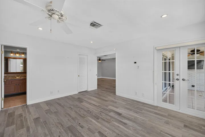 Wood-finish flooring, ceiling fan with light fixture, recessed lighting, and French doors