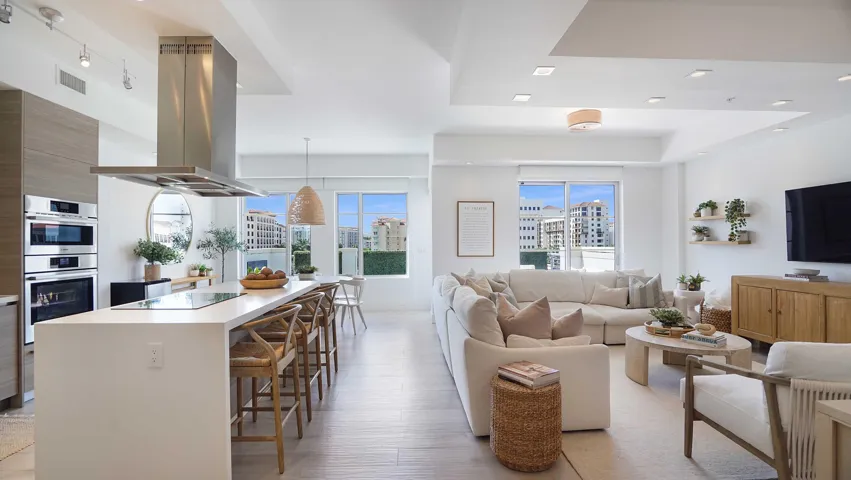 An open composition of living, dining and kitchen spaces, framed by natural light and the terrace beyond.