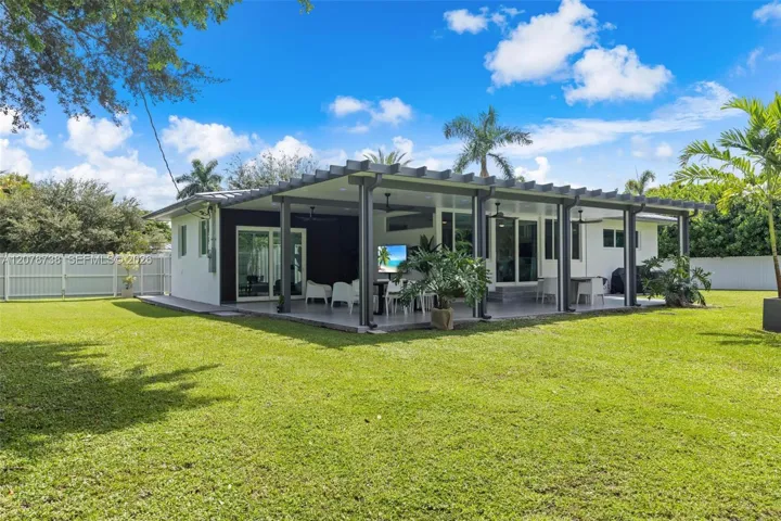 Large windows frame the mature landscaping, while the covered front porch and tropical surroundings give the property the relaxed indoor-outdoor character that makes South Miami living so special.