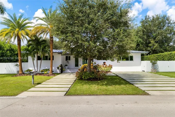 Set beneath mature trees and tropical landscaping, this South Miami home immediately feels private, polished, and welcoming.
