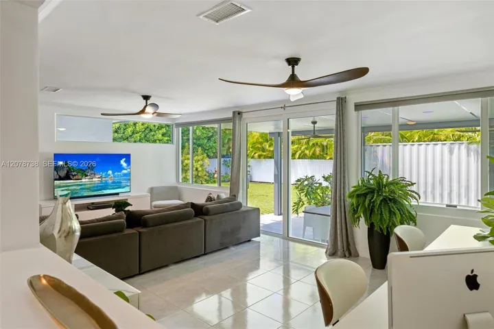 Beyond the main entertaining spaces, the home transitions into a bright secondary living area surrounded by windows and views of the greenery outside.