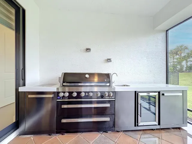Outdoor kitchen with refrigerator, gas grill, sink with hot and cold water.