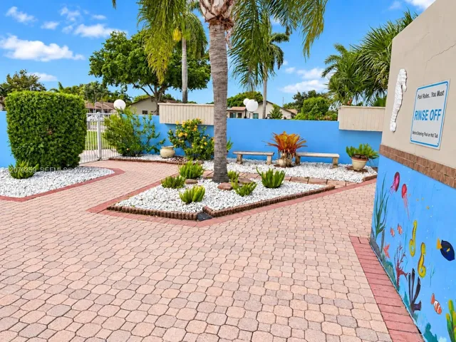 Outdoor recreation and sitting area featuring geometric paver hardscaping, white rock landscaping beds, built-in masonry seating, and mature palm trees