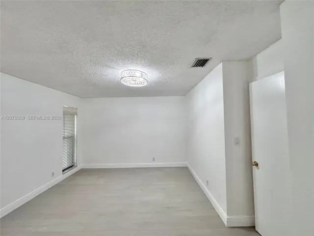 Room featuring luxury vinyl waterproof wood-finish flooring, two windows with integrated blinds, 5 inch baseboards, fresh paint and a decorative drum-style ceiling light fixture and fan.