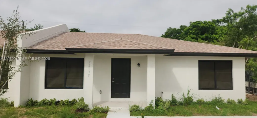 Stucco exterior featuring a neutral color palette, asphalt shingle roof, dark-finished window frames, and a covered front entryway