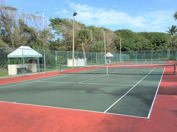 Multiple hard-surface tennis courts featuring perimeter fencing and overhead lighting