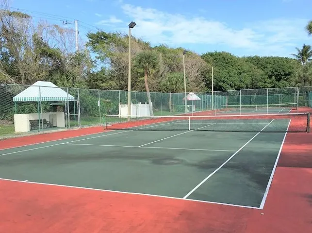 Multiple hard-surface tennis courts featuring perimeter fencing and overhead lighting