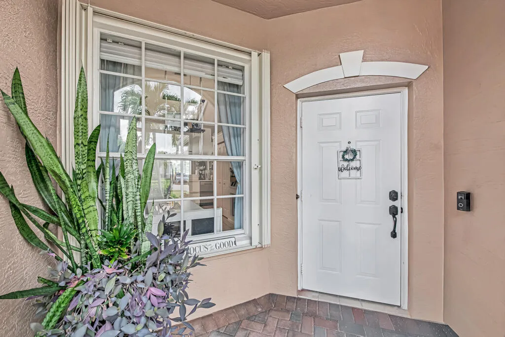 Entryway featuring a white paneled door with black hardware, decorative architrave, and a grid-paned window