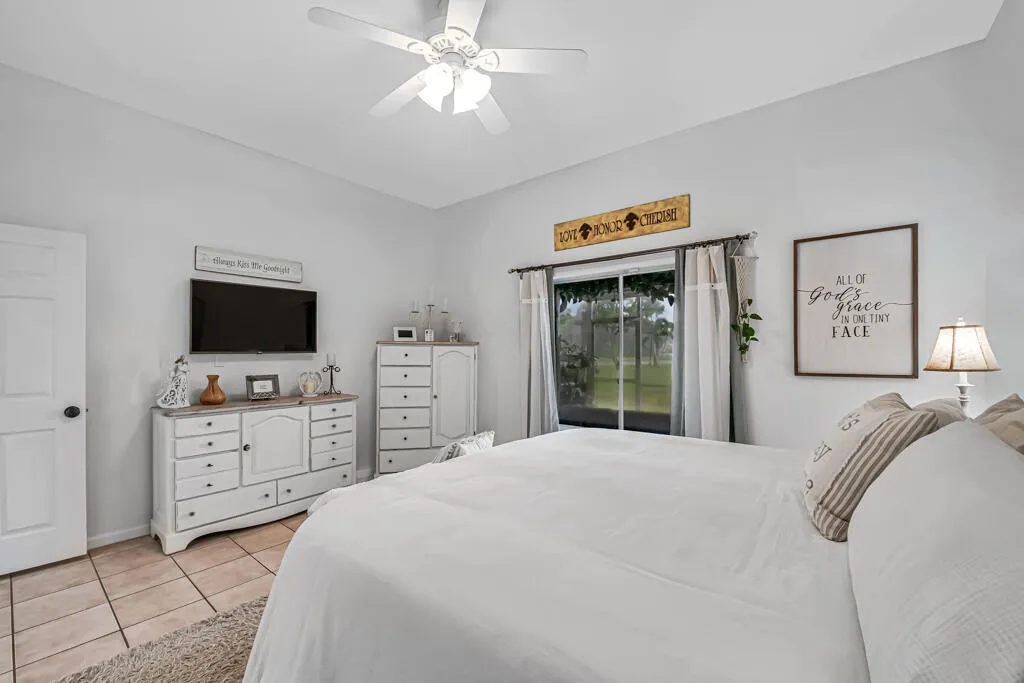 White ceiling fan with integrated lighting, neutral wall finishes, tile flooring, and sliding glass door