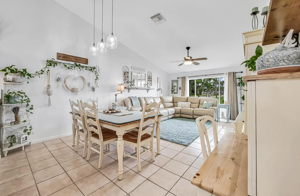 Vaulted ceilings, tile flooring, contemporary pendant lighting, ceiling fan, and sliding glass door