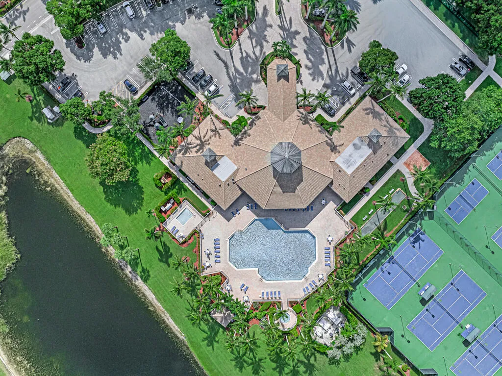 Central community building featuring a swimming pool, adjacent hot tub, and multiple tennis courts