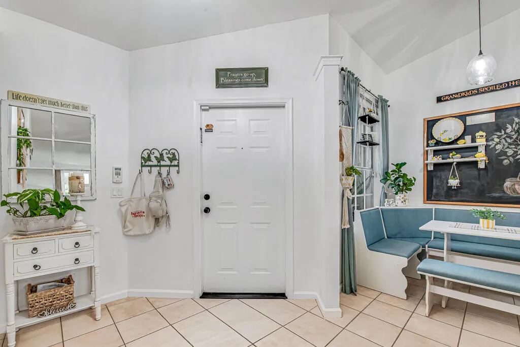 Tile flooring, vaulted ceiling, built-in banquette seating with cushions, window with drapes, and a panel door