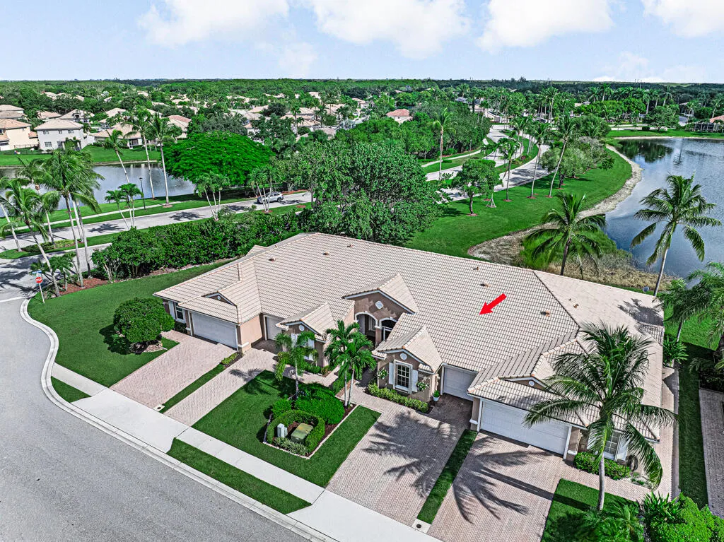 Expansive property featuring a tiled roof, multiple garage entrances, and landscaped grounds with mature palm trees