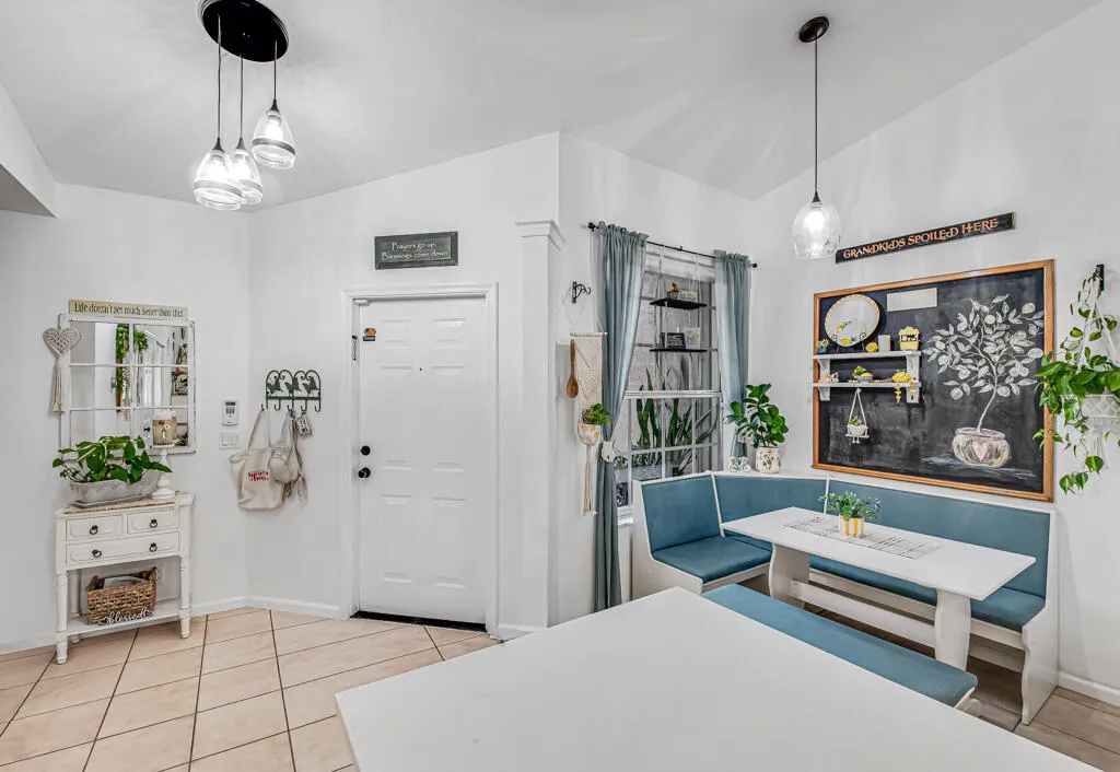 Vaulted ceiling with pendant lighting, tile flooring, paneled entry door, and a built-in corner banquet