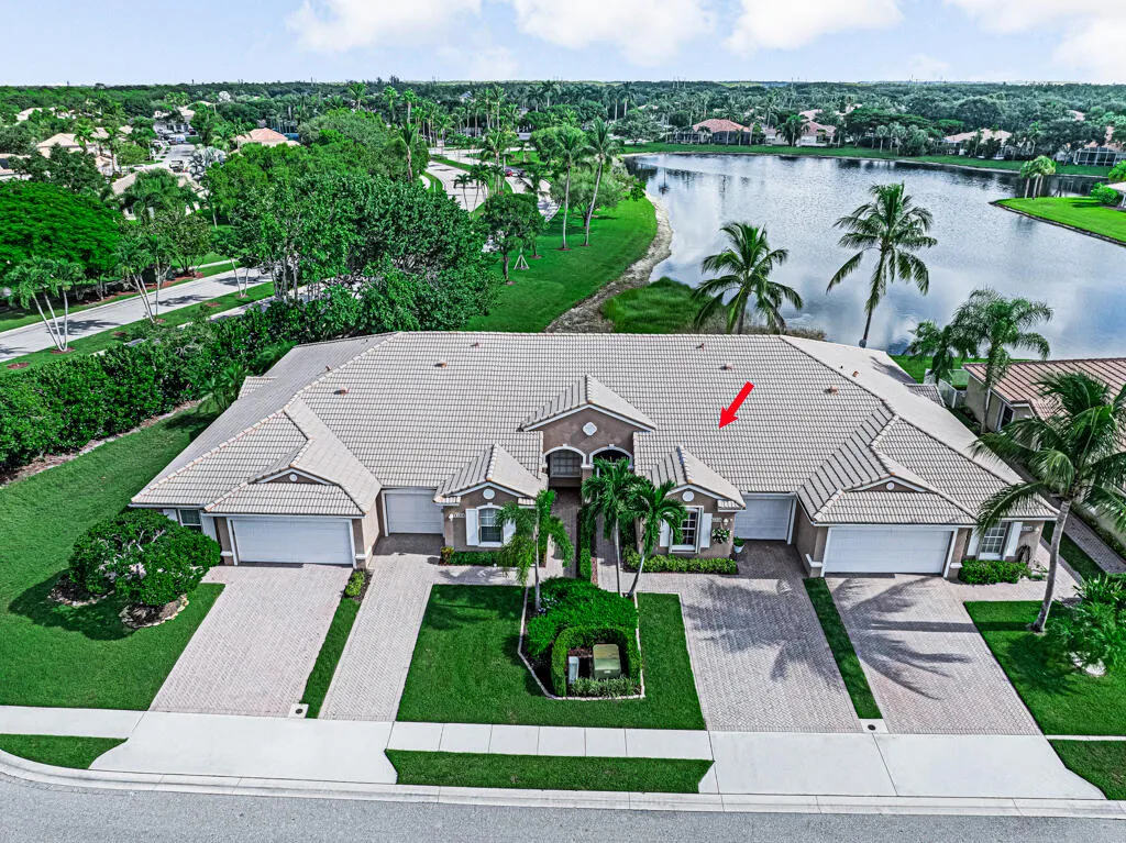 Waterfront property featuring a tile roof, paved driveways, a landscaped front yard, and an attached garage