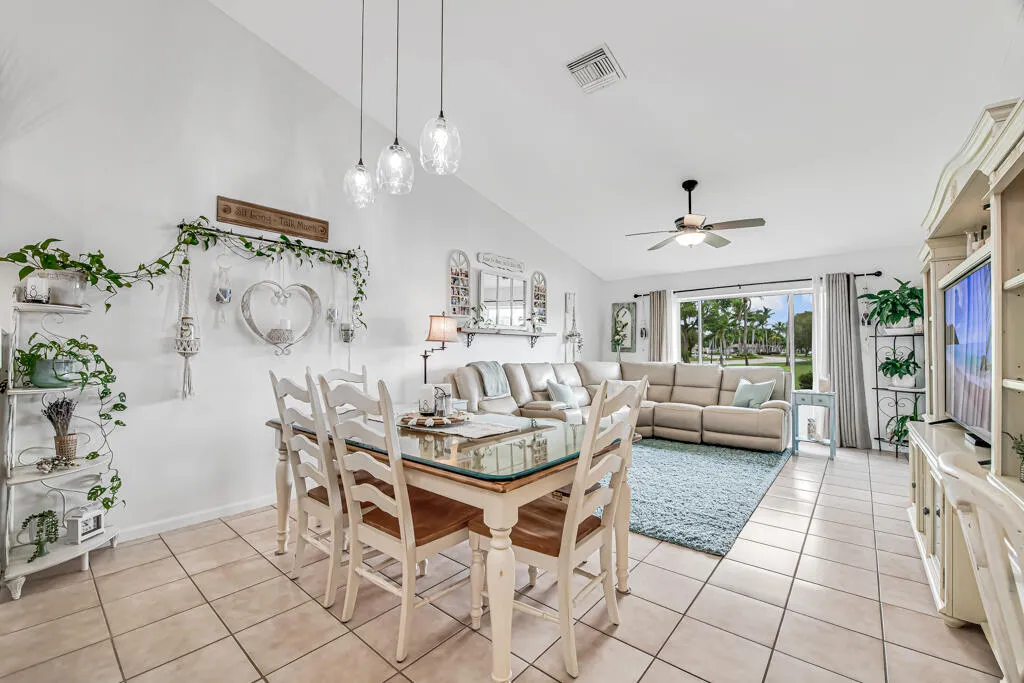 Vaulted ceilings with pendant lighting and a ceiling fan, large windows, and tile flooring