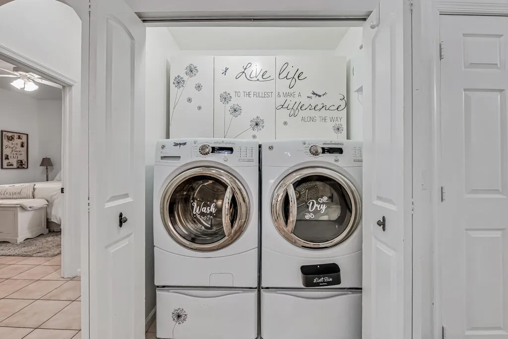 Full-size laundry appliances within a dedicated closet space, featuring white paneled doors and storage cabinetry above