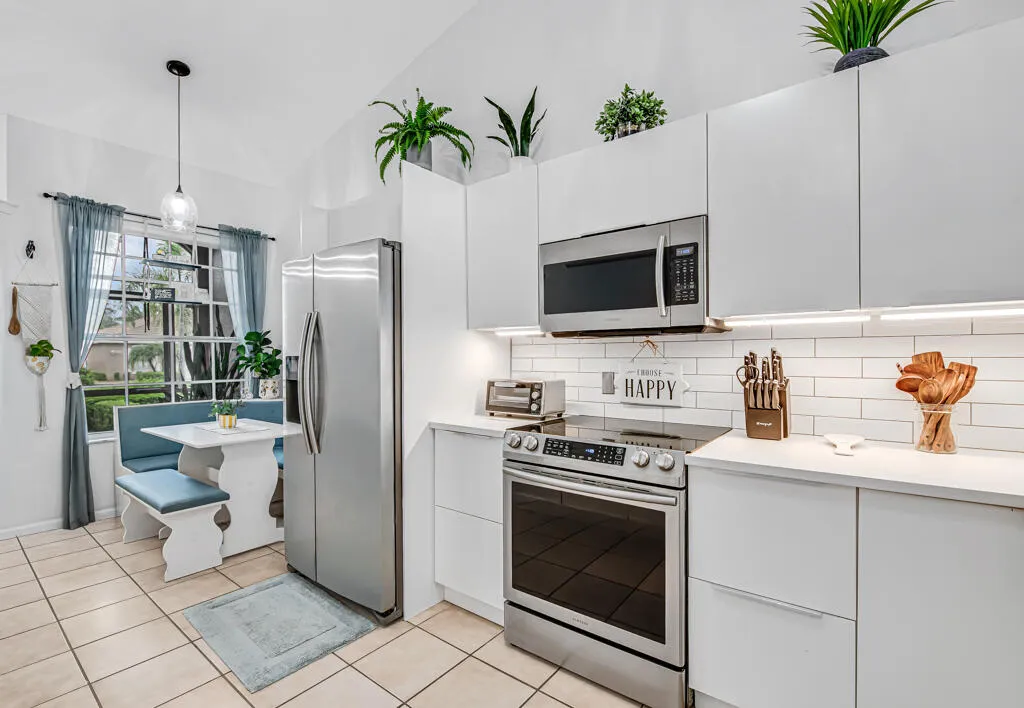 Vaulted ceilings, subway tile backsplash, stainless steel appliances, white flat-panel cabinetry, and tile flooring