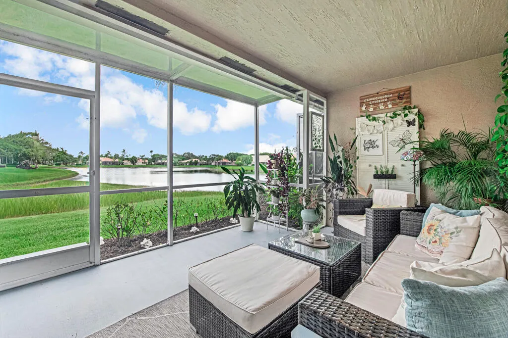 Screened patio with a painted concrete floor, featuring a prominent water body, verdant landscaping, and a textured ceiling