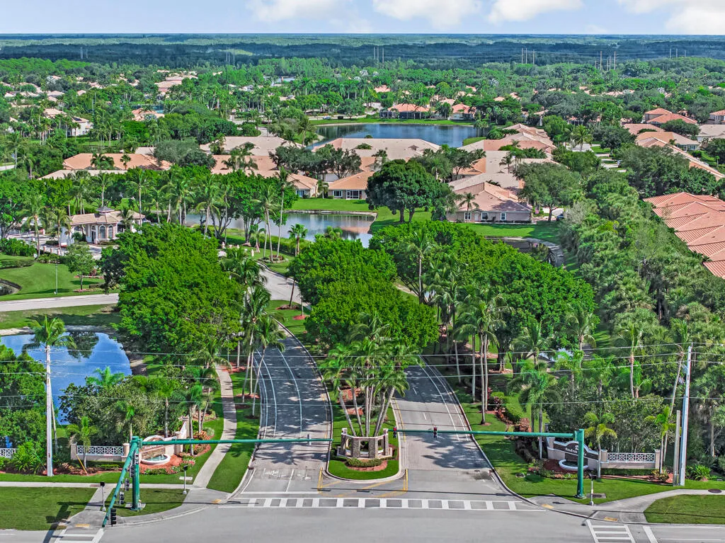 Gated community entrance featuring structured landscaping, multiple residential structures, and a prominent water feature