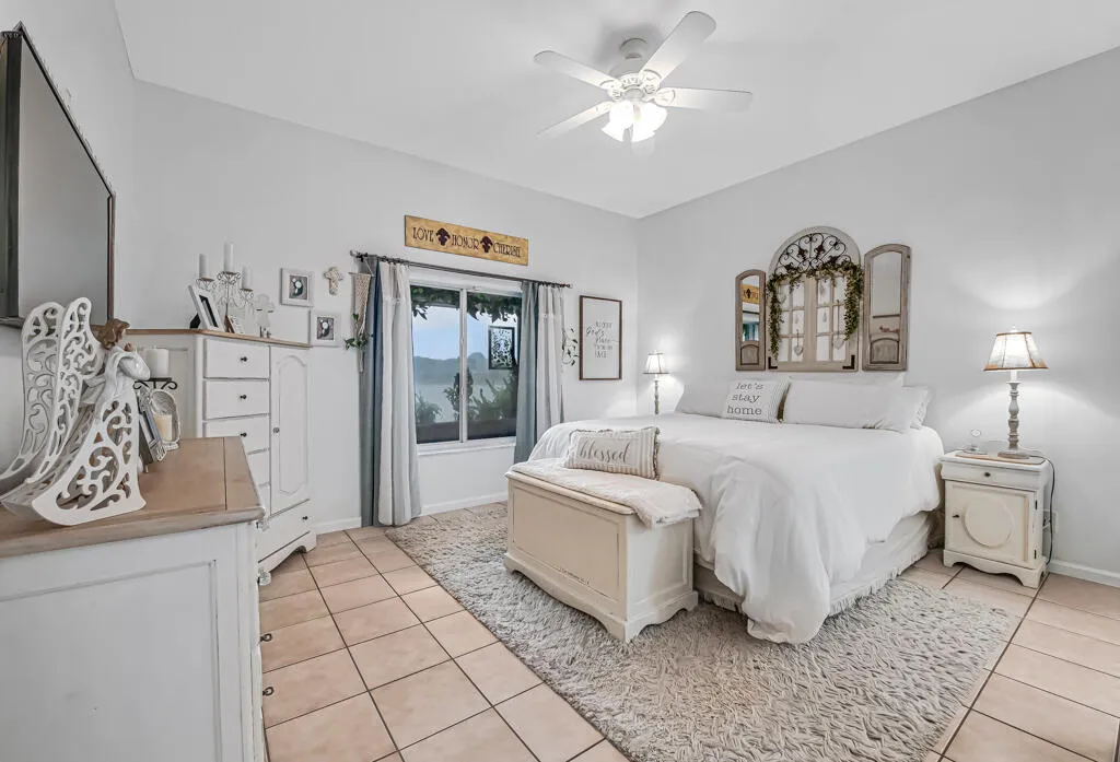 Neutral wall paint, ceiling fan with integrated lighting, tile flooring, and a large window