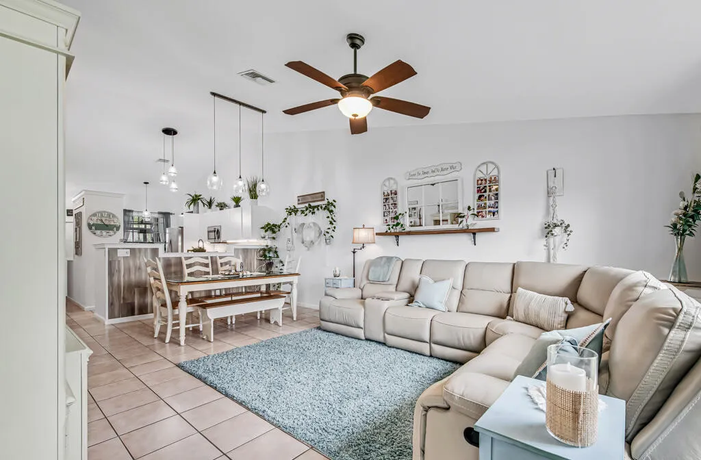 Vaulted ceiling with a ceiling fan, tile flooring, pendant lighting, and an open-concept layout