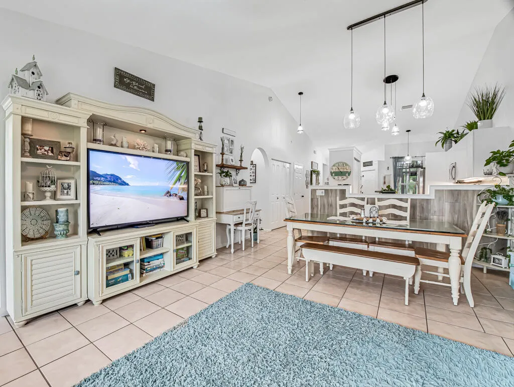 Vaulted ceilings, tiled flooring, built-in shelving, and a multi-pendant lighting fixture