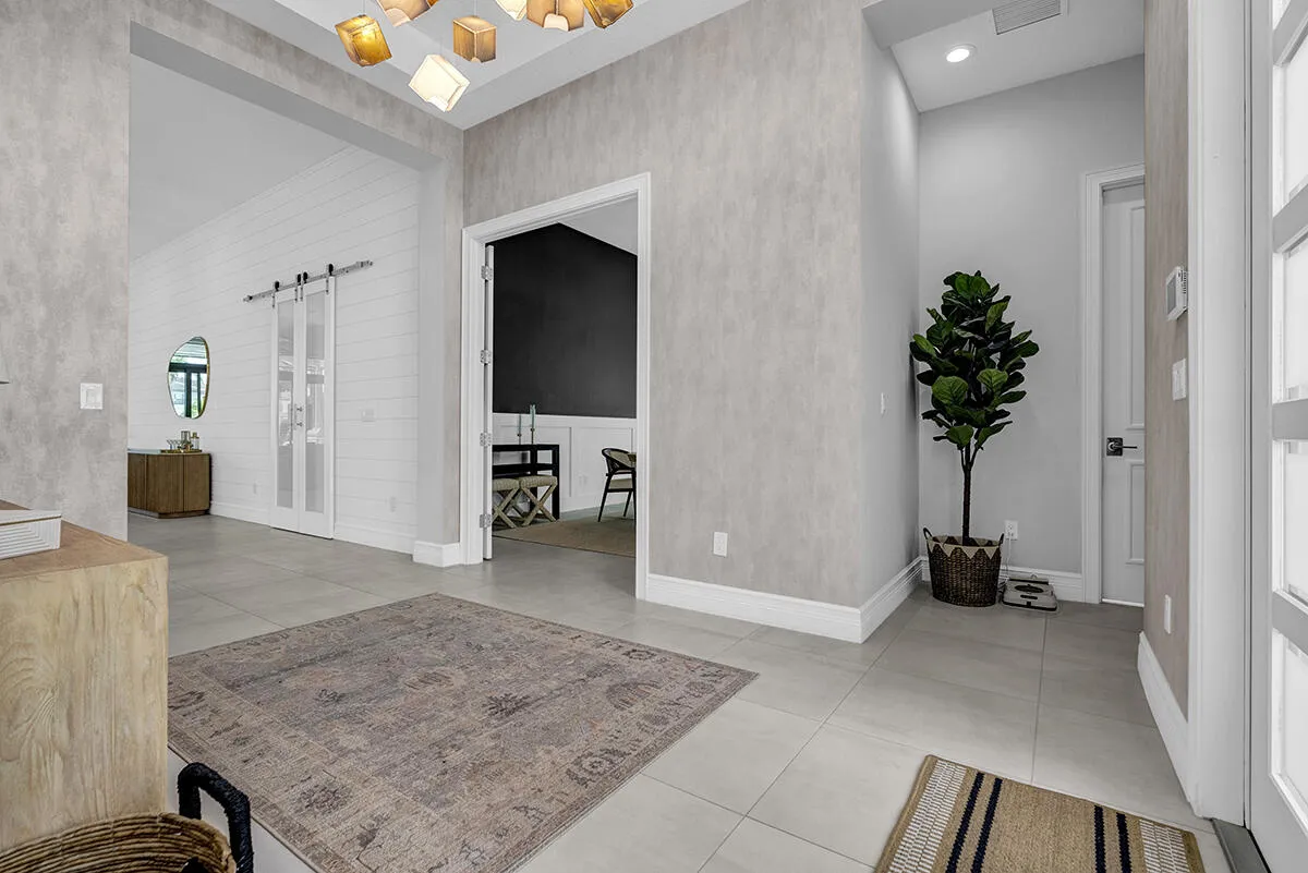 Entryway featuring light-toned tile flooring, textured wall finishes, and a contemporary ceiling light fixture