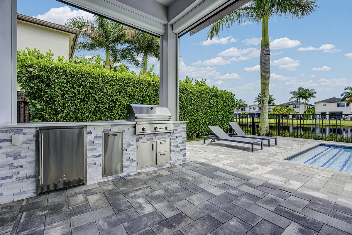 Outdoor kitchen featuring a stainless steel grill, beverage refrigerator, and built-in cabinetry