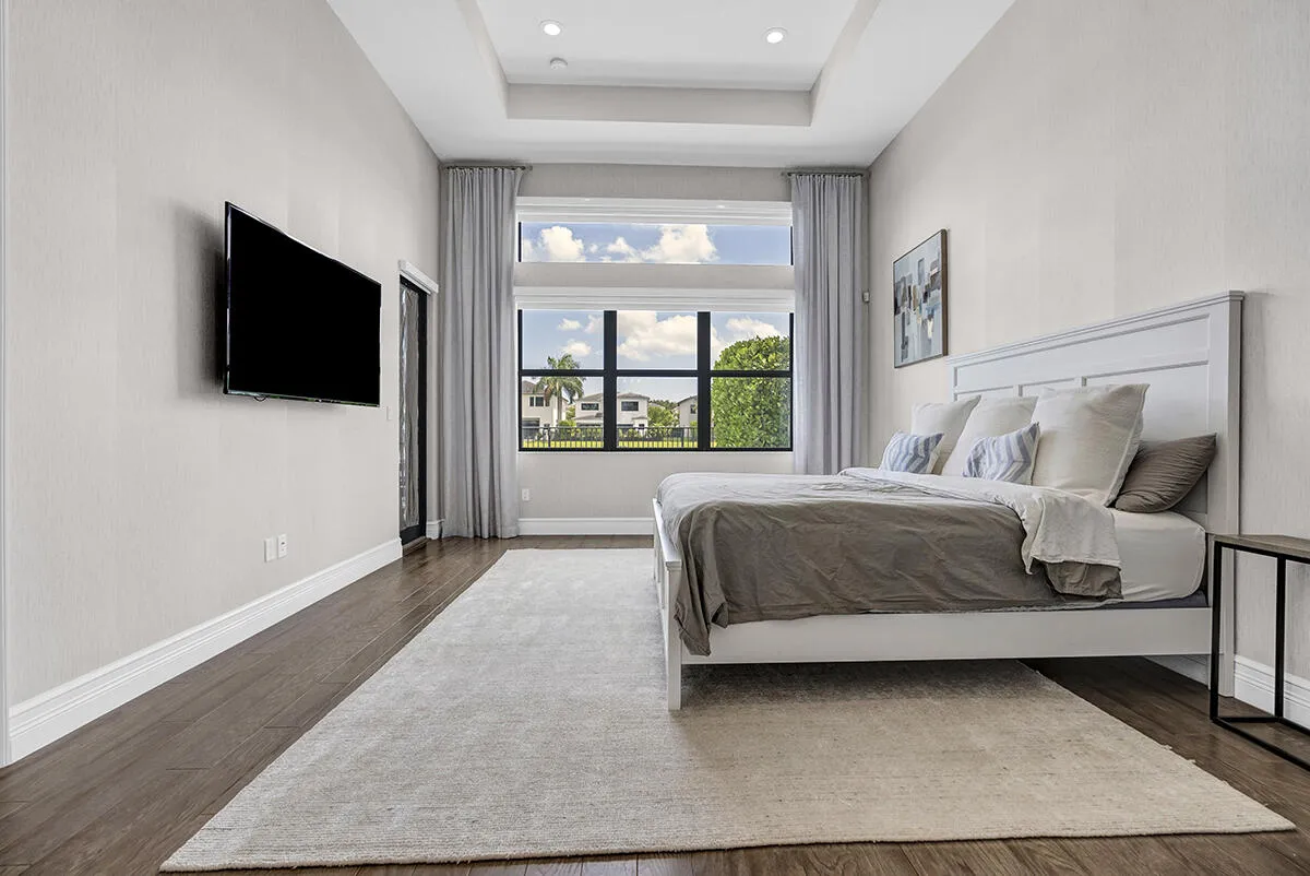 Room featuring a tray ceiling with recessed lighting, large windows, wood-finish flooring, and a sliding glass door