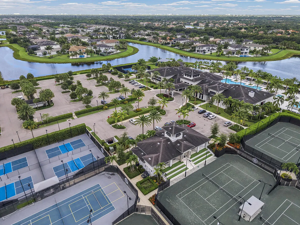 Aerial perspective showcasing a community clubhouse with multiple pools, surrounded by tennis and pickleball courts