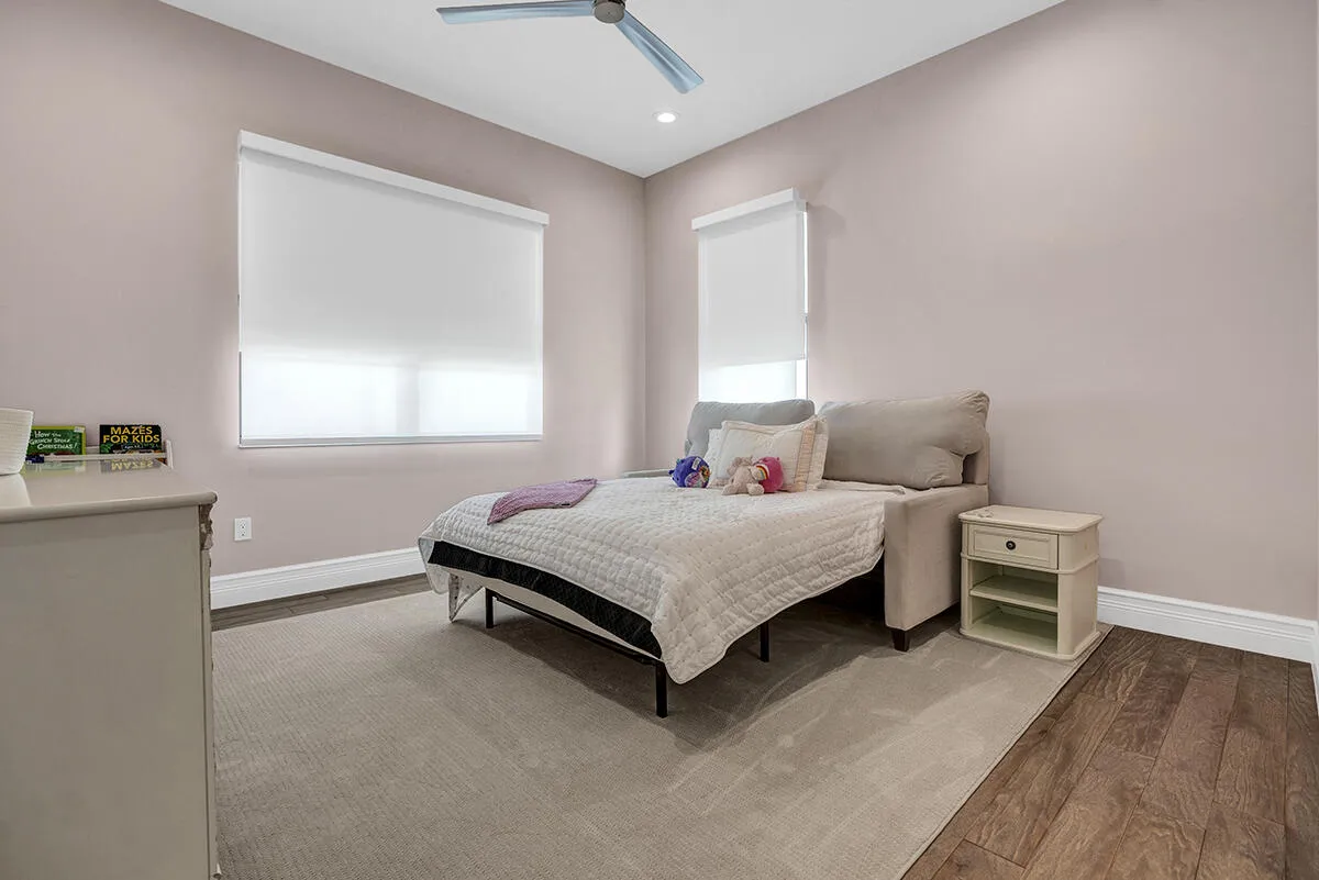 Recessed lighting illuminates a room featuring a ceiling fan, wood-finish flooring, and white baseboards