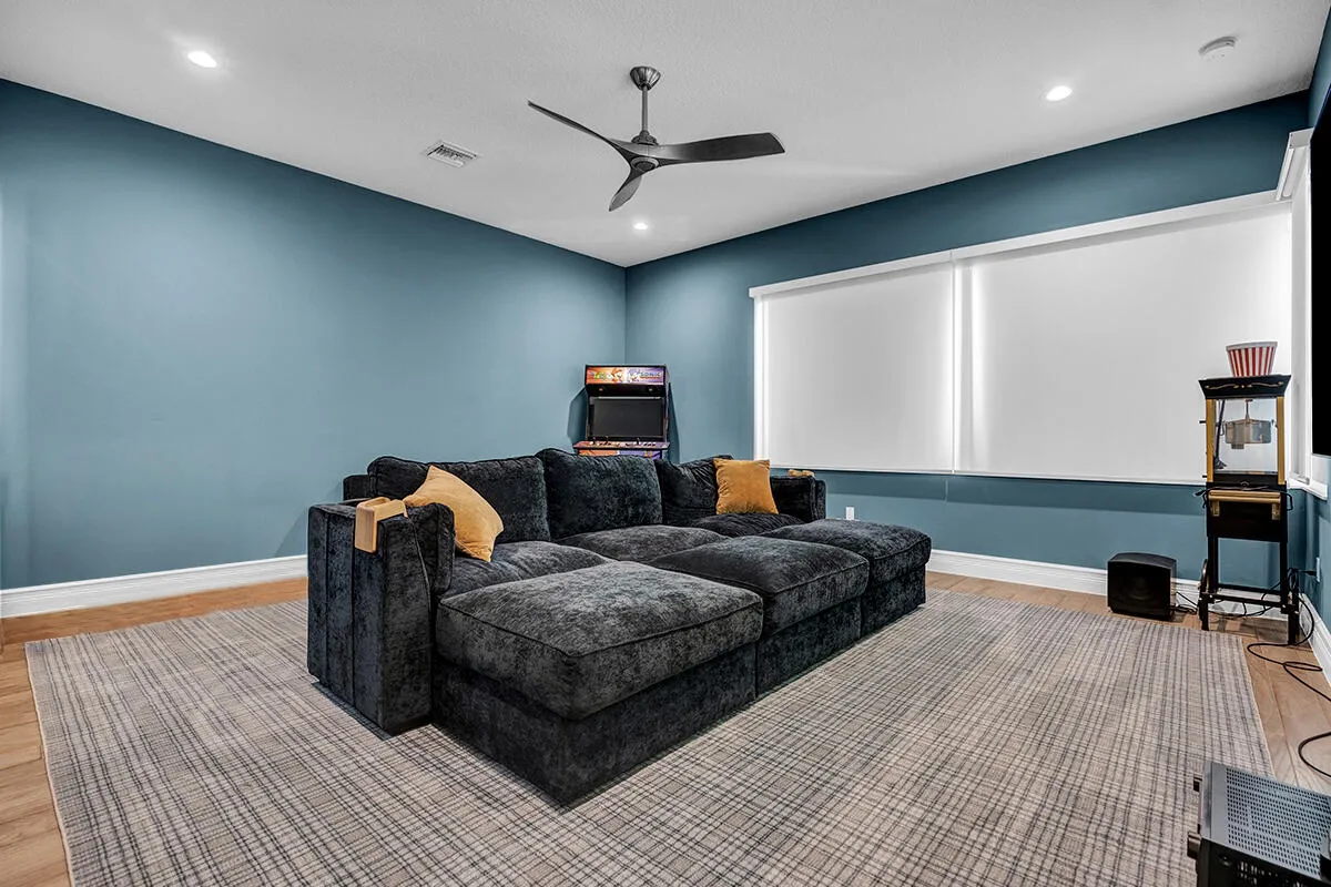 Spacious entertainment room featuring recessed lighting, a ceiling fan, wood-finish flooring, and bright white window treatments