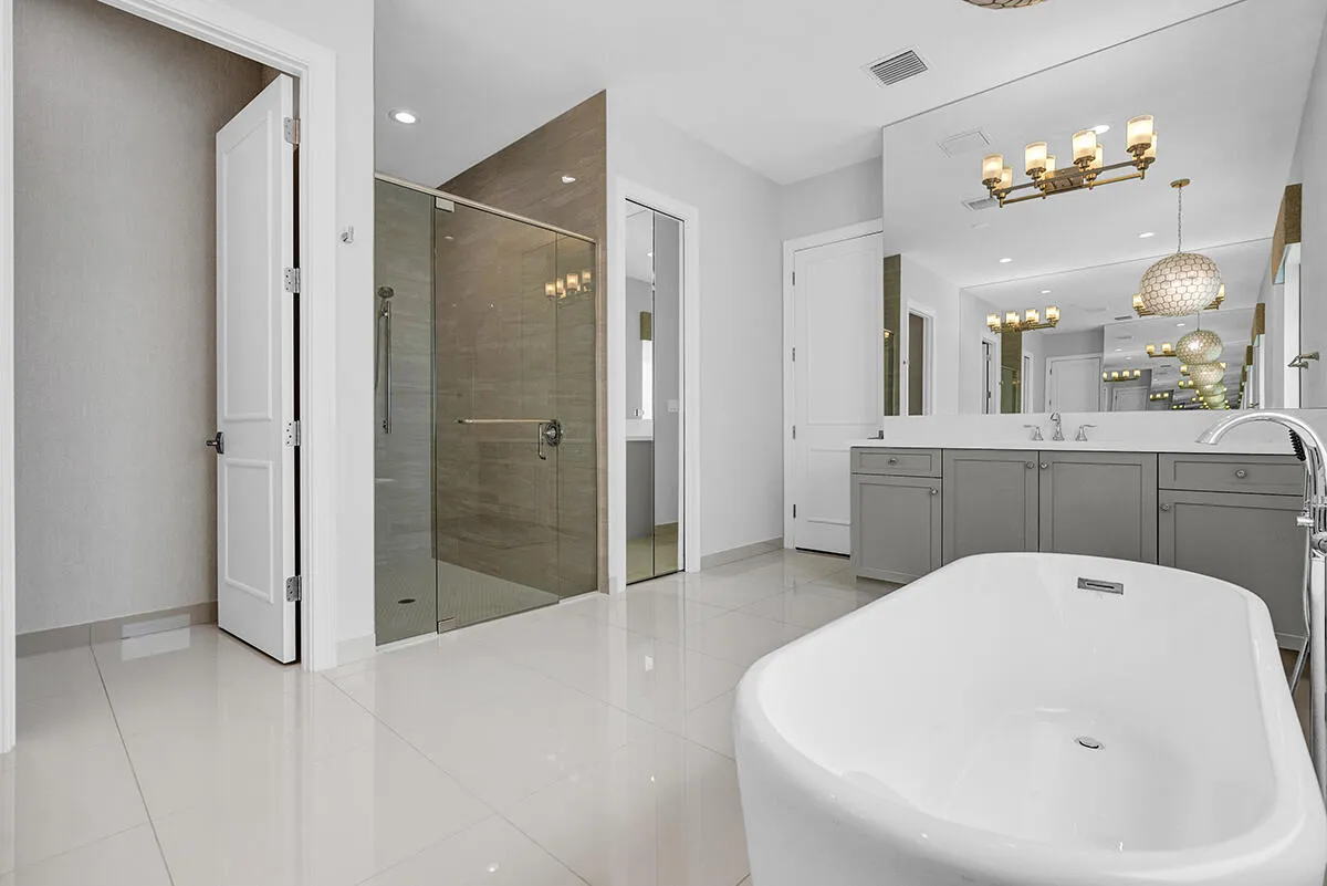 Freestanding soaking tub with a floor-mounted faucet, complemented by a large vanity with a white countertop and dual undermount sinks