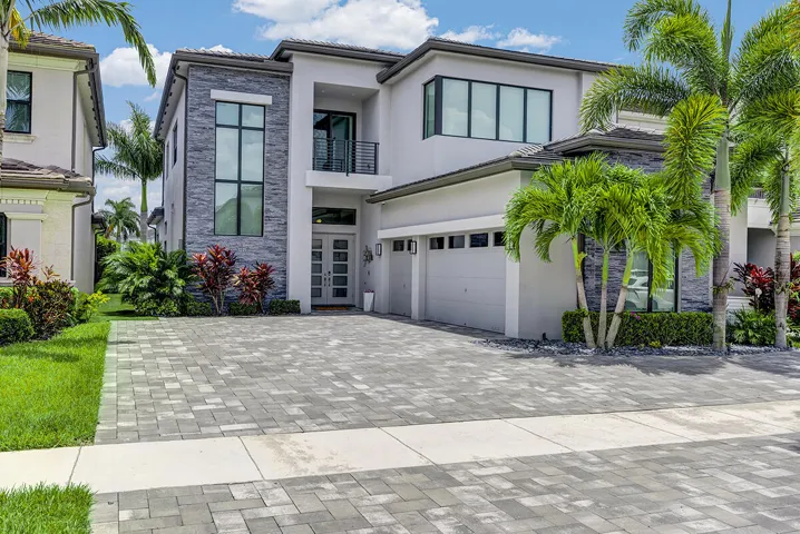 Contemporary two-story residence featuring a paver driveway, an integrated two-car garage, and a modern grey and stone facade