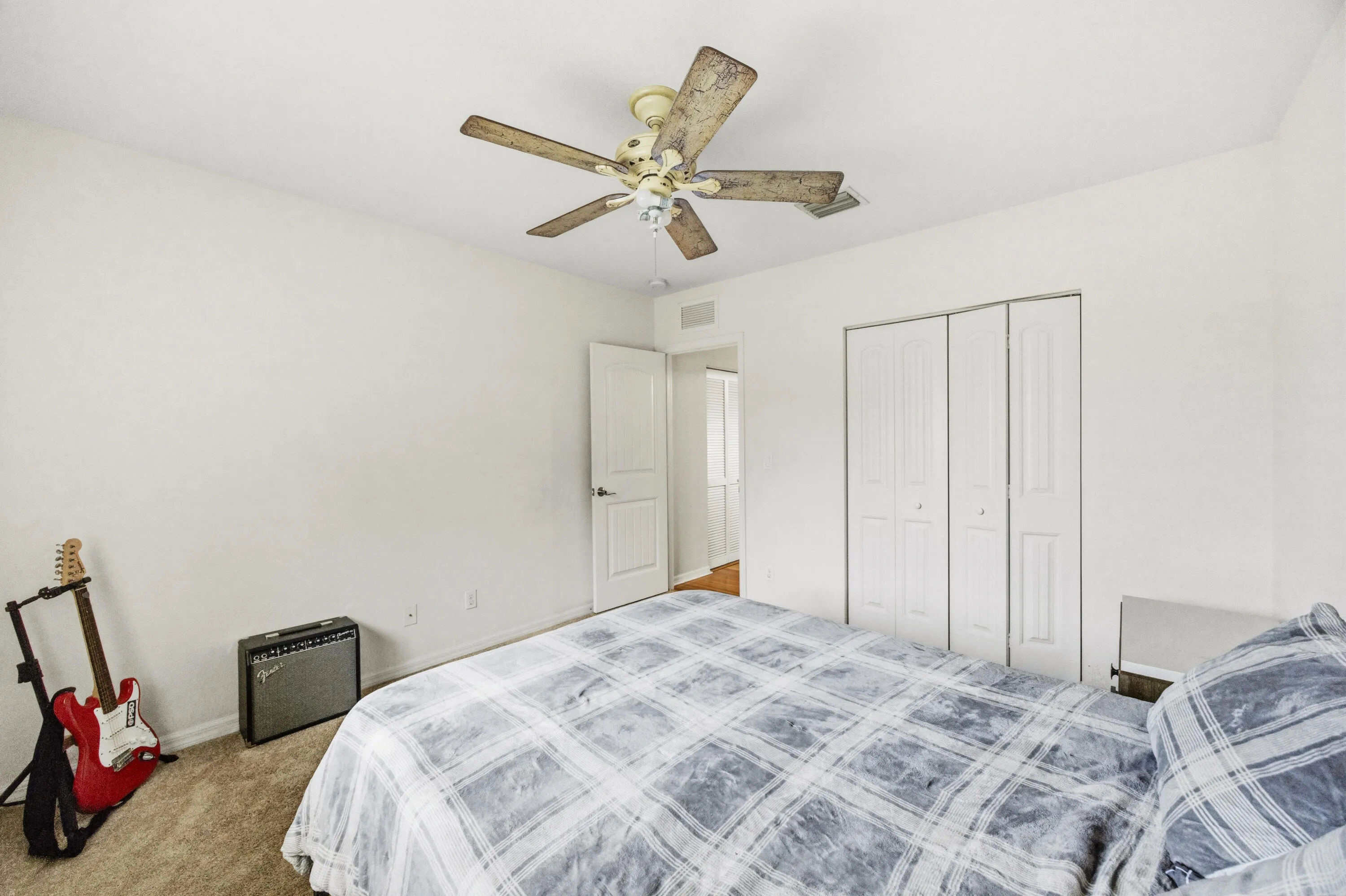 Neutral wall paint with textured carpeting, a ceiling fan, and bi-fold closet doors