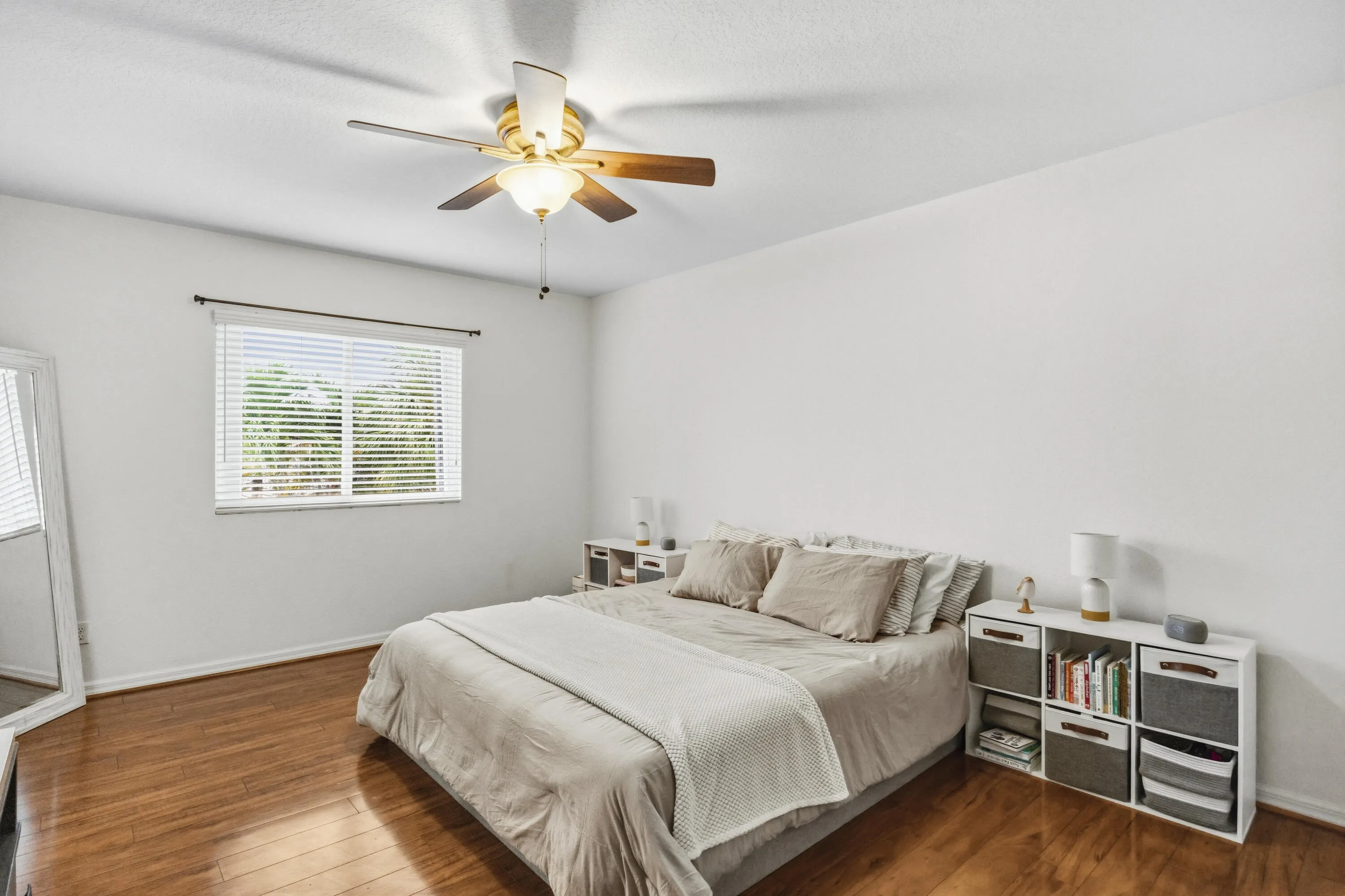 Wood-finish flooring, white walls, window with blinds, and a ceiling fan