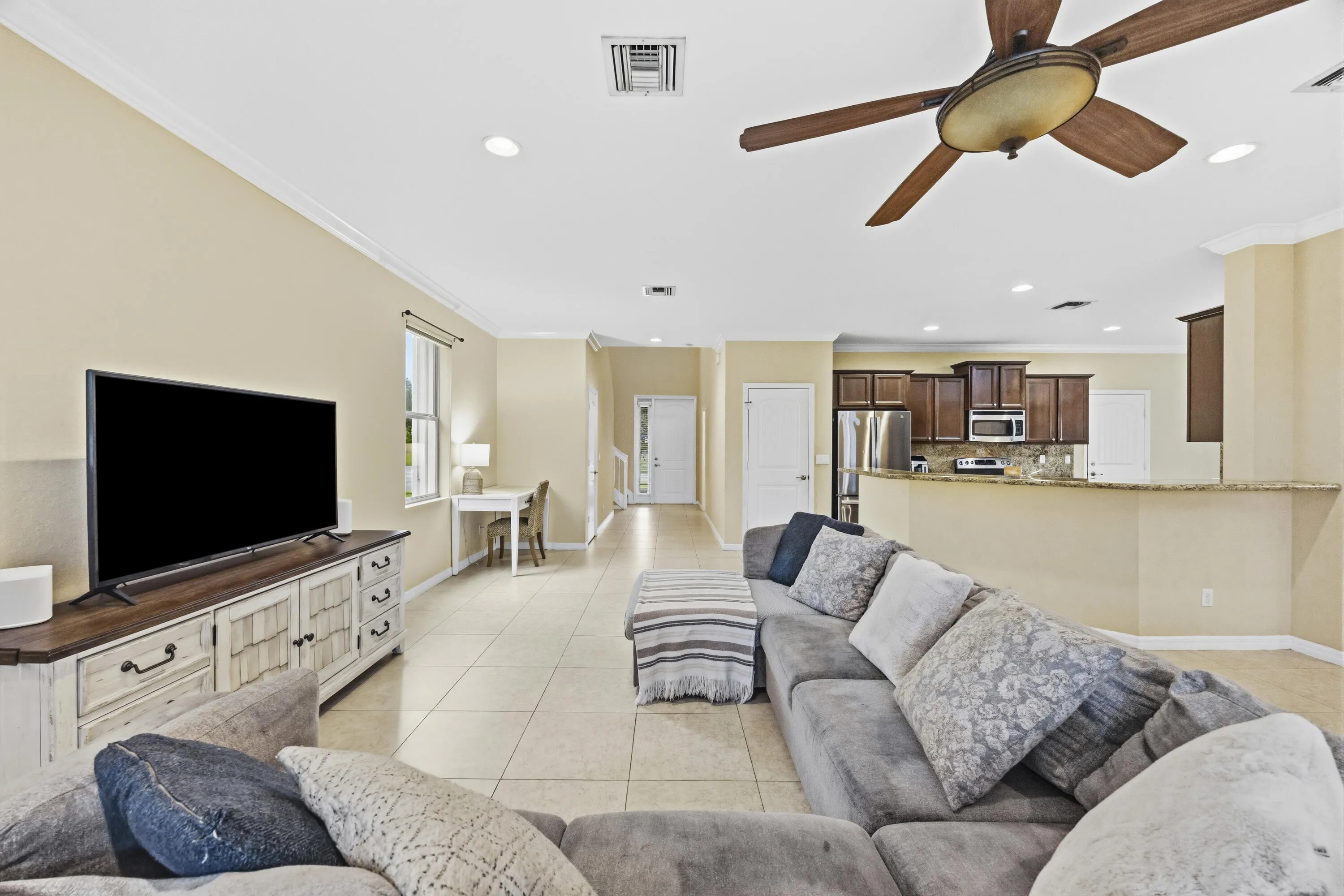 Spacious open-concept living area with tile flooring, crown molding, and recessed lighting
