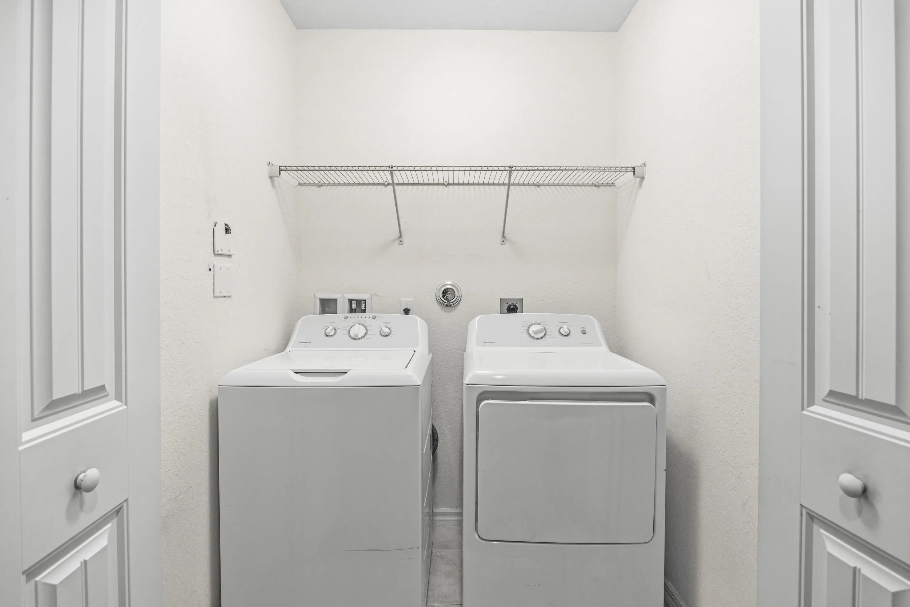 Laundry area with wire shelving, washer, and dryer connections