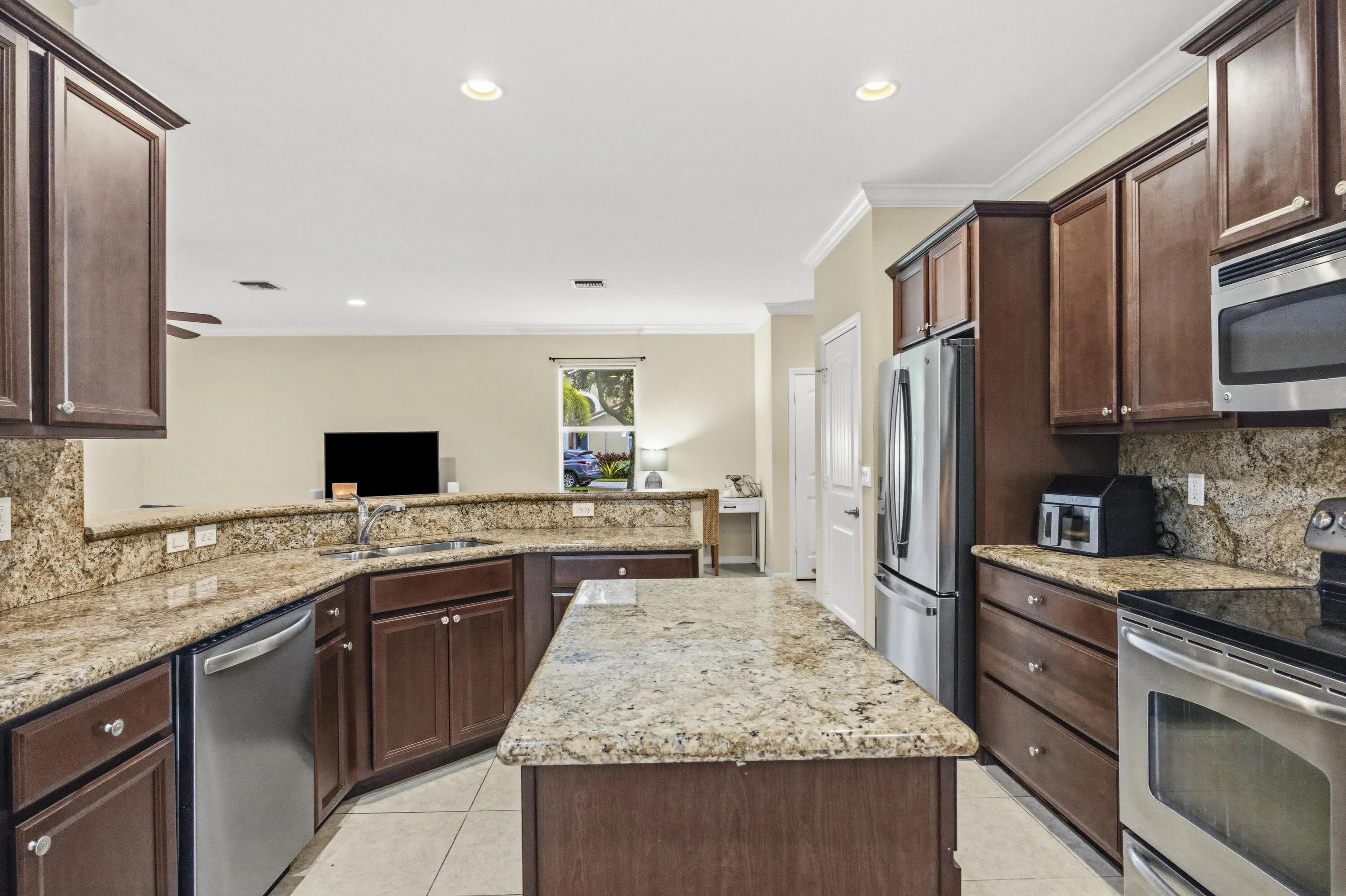Kitchen featuring wood-finish cabinetry, stone countertops, stainless steel appliances, a center island, and recessed lighting
